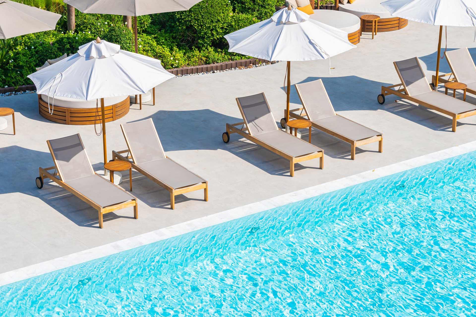 umbrella and deck chair around outdoor swimming pool in hotel resort e1653991645944.jpg
